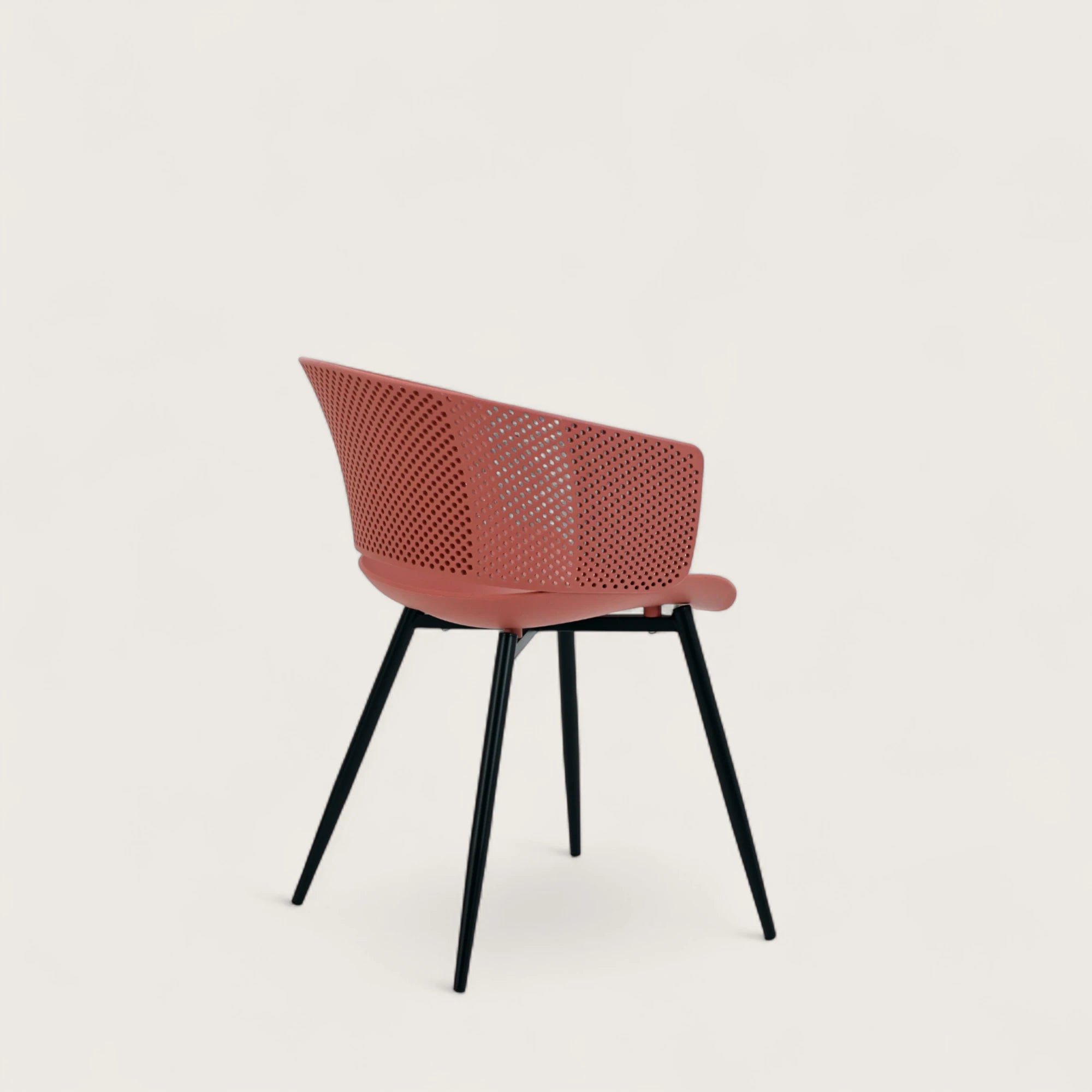 Sedia con scocca in polipropilene colore terracotta, schienale avvolgente e gambe in metallo nero opaco, ideale per sale da pranzo, cucine e spazi contract.