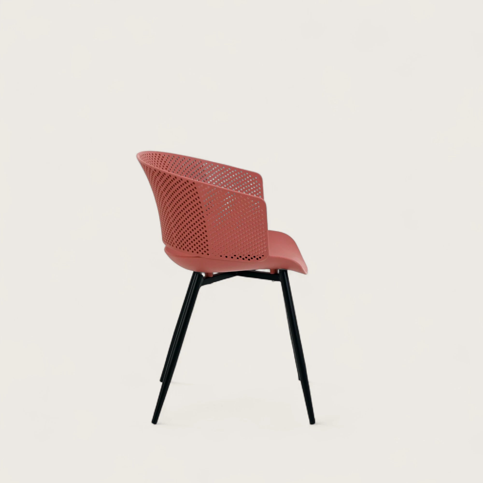Sedia con scocca in polipropilene colore terracotta, schienale avvolgente e gambe in metallo nero opaco, ideale per sale da pranzo, cucine e spazi contract.