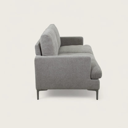 Il divano 2 posti è rivestito in tessuto tortora, con una seduta ampia completata da due cuscini pieni. Il design moderno, linee pulite e piedini in metallo conferiscono stabilità e un tocco di stile contemporaneo, rendendo il divano adatto a soggiorni eleganti e funzionali.