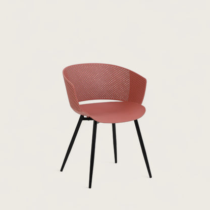 Sedia con scocca in polipropilene colore terracotta, schienale avvolgente  e gambe in metallo nero opaco, ideale per sale da pranzo, cucine e spazi contract.
