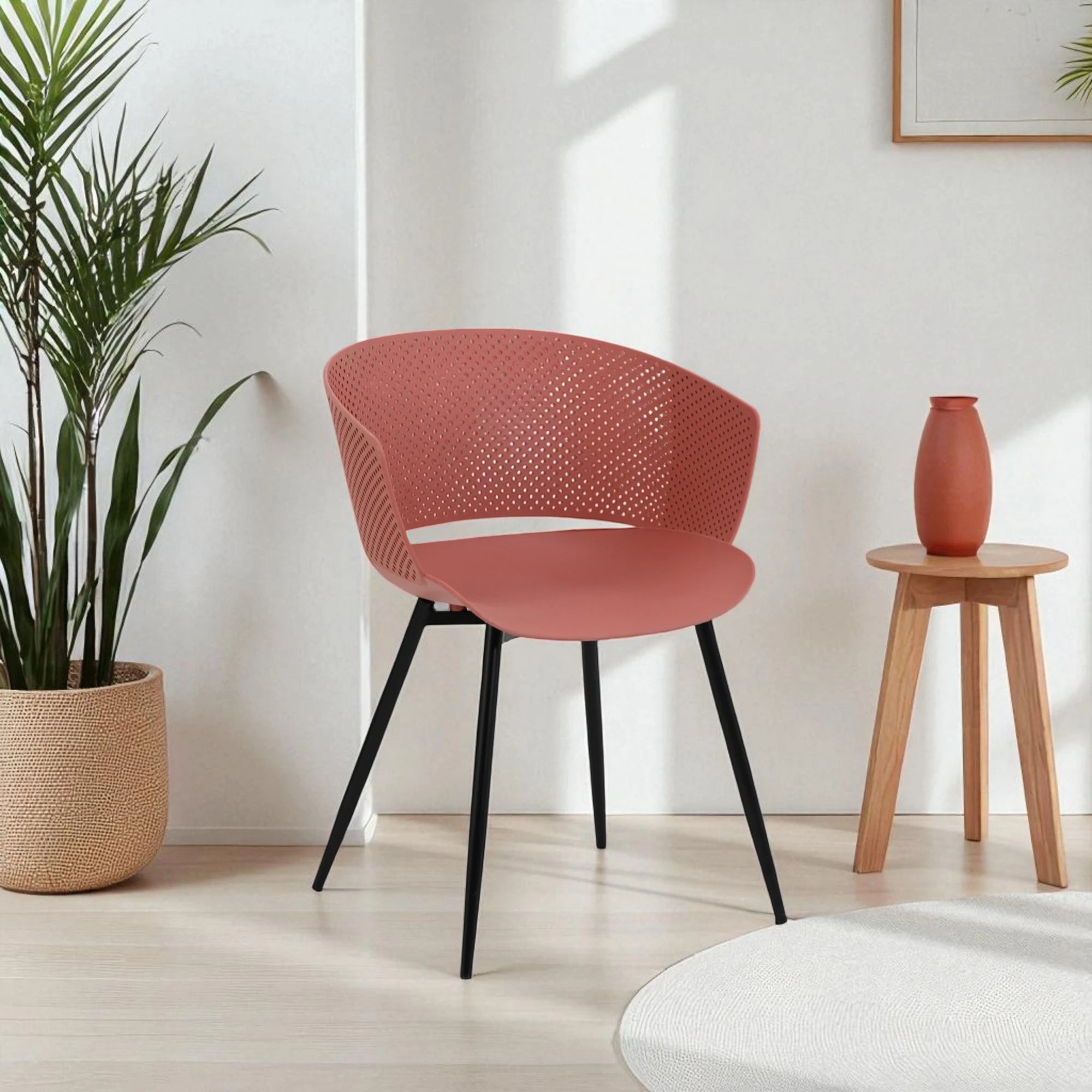 Sedia dal design moderno con scocca in polipropilene traforato, schienale avvolgente, seduta inclinata e gambe in metallo nero opaco, ideale per sale da pranzo, cucine e spazi contract.